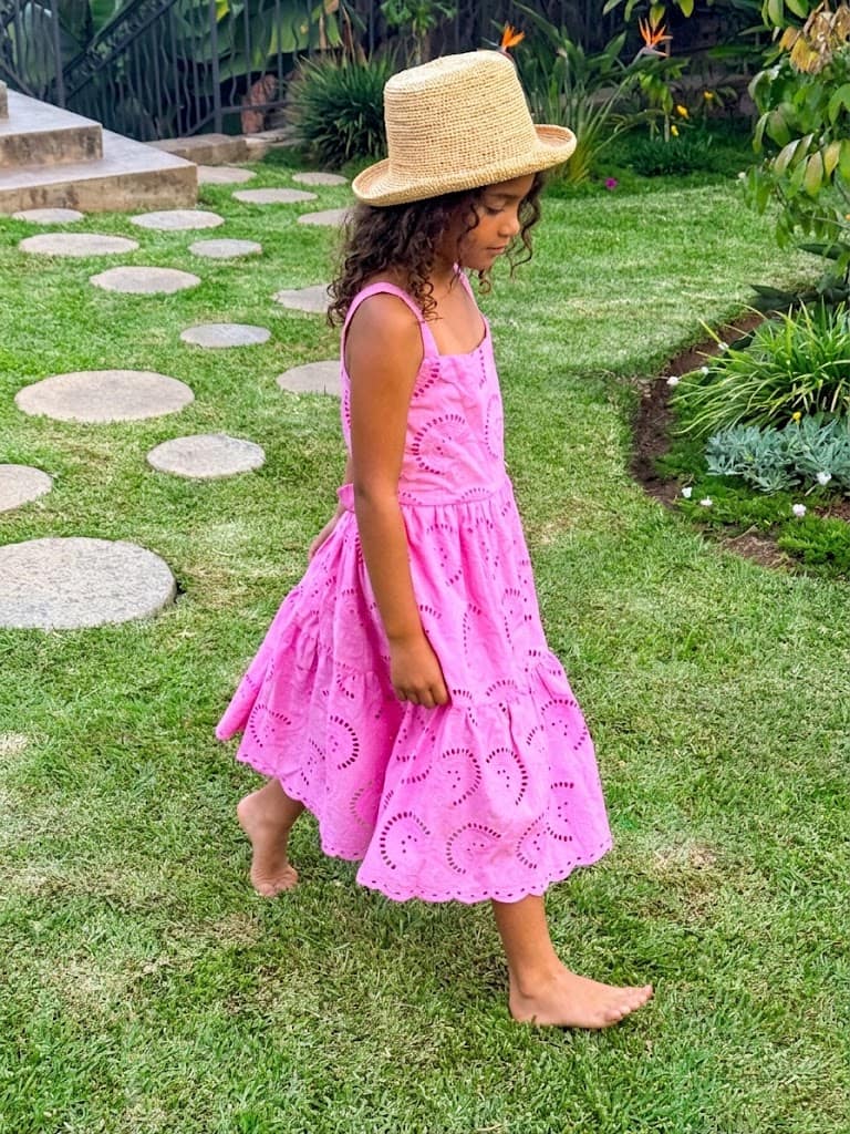 Enfant en robe rose et chapeau dans le jardin