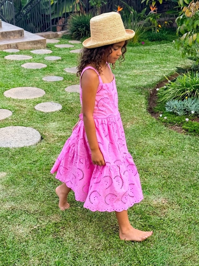 Enfant en robe rose et chapeau dans le jardin