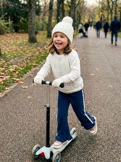 Enfant en trottinette portant le pantalon Onja marine à volant et croquet écru