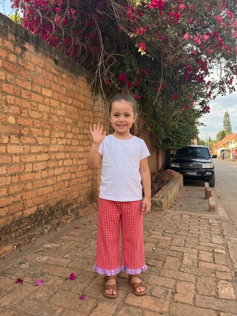 Enfant en pantalon à carreaux roses sous les bougainvillées